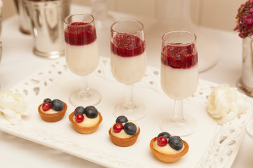 Delicious tartlets filled with fruits and pannacotta in glass. Table set.