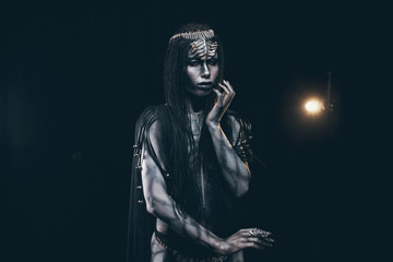 Young woman in image of humanoid and extraterrestrial alien on background of light.