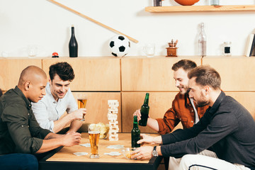 multicultural men playing cards while spending time together in cafe