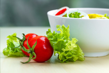 Fresh, healthy vegetable salad with lettuce, cherry tomatoes, onion, feta cheese, lemon, sprinkled with spices in a plate. Proper nutrition and right food. Diet