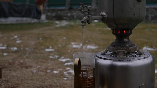 poured tea in a mug in the backyard during the cold season. big old samovar. slow motion