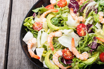 Mix of salad with shrimps , avocado and cherry tomatoes . Healthy food background