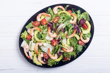 Mix of salad with shrimps , avocado and cherry tomatoes . Healthy food background