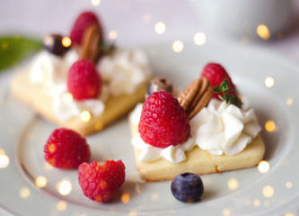 Cakes with whipped cream and berries. Holiday lights.