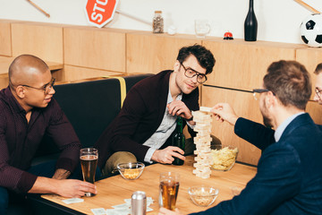 multiethnic businessmen with beer playing blocks wood game in cafe