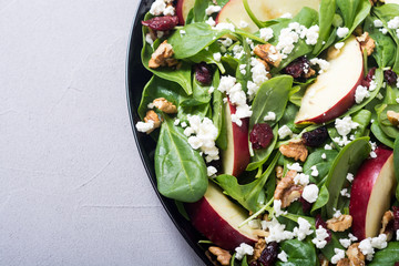 Autumn spinach salad with apple , cheese , walnut and dried cranberry . Healthy vegetarian food