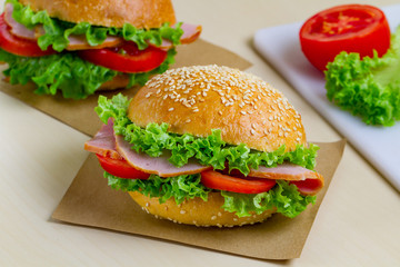 Appetizing sesame buns with fresh lettuce, tomato and ham for snack. Homemade sandwiches
