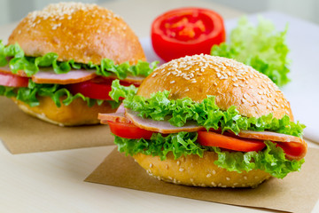 Appetizing sesame buns with fresh lettuce, tomato and ham for snack. Homemade sandwiches