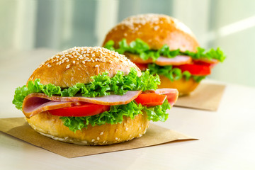 Appetizing sesame buns with fresh lettuce, tomato and ham for snack. Homemade sandwiches