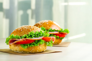 Appetizing sesame buns with fresh lettuce, tomato and ham for snack. Homemade sandwiches