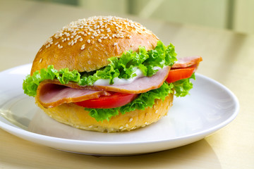Appetizing sesame buns with fresh lettuce, tomato and ham for snack. Homemade sandwiches