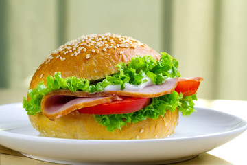 Appetizing sesame buns with fresh lettuce, tomato and ham for snack. Homemade sandwiches