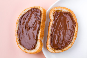 Pieces of long loaf with chocolate, nut paste on a plate. Nut chocolate cream sandwiches on a breakfast. Top view