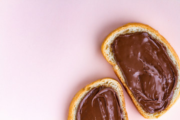 Pieces of loaf with chocolate paste on a pink background. Chocolate sandwiches with nut paste on a breakfast. Copy space