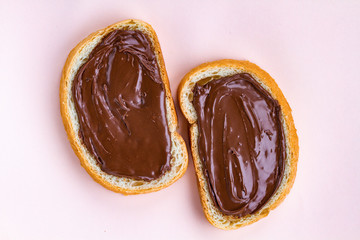 Pieces of loaf with chocolate paste on a pink background. Chocolate sandwiches with nut paste on a breakfast.