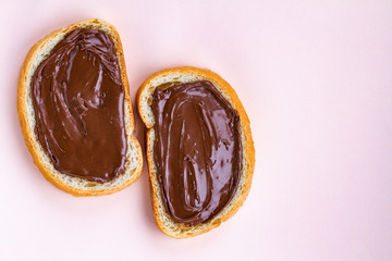 Pieces of loaf with chocolate paste on a pink background. Chocolate sandwiches with nut paste on a breakfast. Copy space