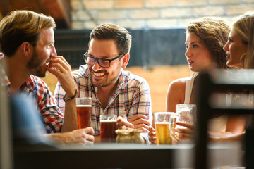 Young cheerful people in the beer pub drinking and having good time