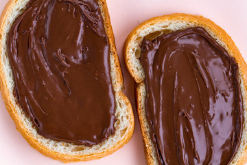 Pieces of loaf with chocolate paste on a pink background. Chocolate sandwiches with nut paste on a breakfast.