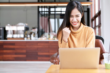 Young attractive asian female student using laptop computer smiling with excited at cafe coffee shop. Happy asian success woman, worker or entrepreneur in smart casual wearing with copy space concept.