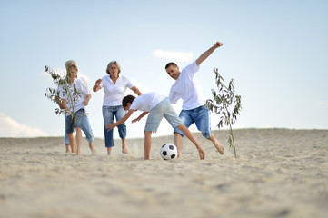Happy family playing football on a beach in summer day