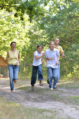Obraz premium Portrait of happy family of four in autumn park running