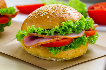 Appetizing sesame buns with fresh lettuce, tomato and ham for snack. Homemade sandwiches