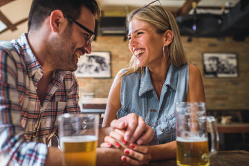 Young cheerful couple in the beer pub drinking and having good time