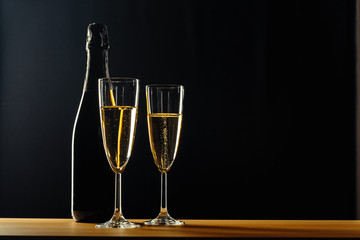bottle of champagne and glasses over dark background