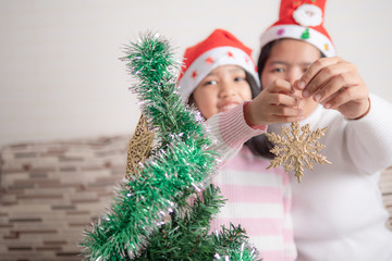 Asian little girl with mother decorating christmas tree for party with happiness