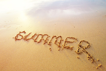 Summer letters handwritten in sand on beach