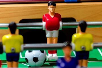 Toy football player in a red shirt with a ball on the field