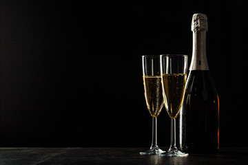 bottle of champagne and glasses over dark background