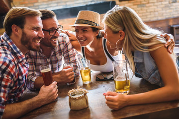 Young cheerful people in the beer pub drinking and having good time