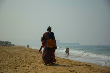 Indian woman street vendor walking on the beach