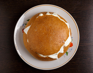 Bread with sausage, cheese and sour cream on a plate on the table. The view from the top.