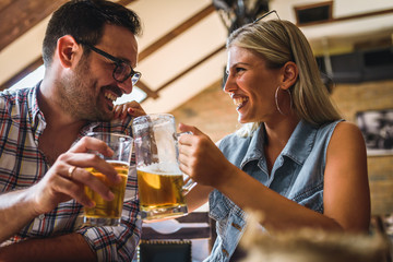 Young cheerful couple in the beer pub drinking and having good time