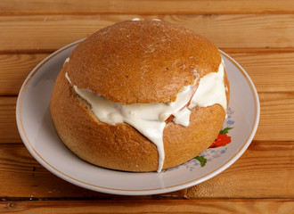 Bread with sausage, cheese and sour cream on a plate on the table.