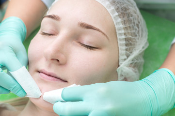 Beautician hands cleans black dots on the face. Closeup of head