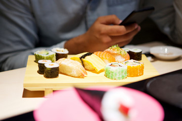 male hands with mobile phone at sushi bar © mimagephotos