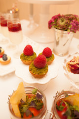Delicious tartlets filled with fruits. Dessert in glass jags. Table set.