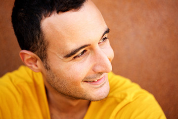 Fototapeta premium Close up portrait of happy latin man looking away against brown background