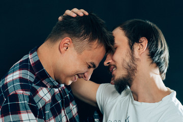 two guys hugging on a dark background
