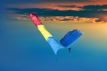 Paraglider flying Romanian flag on the sky, against sunset scene