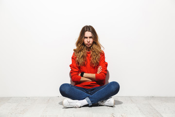 Full length photo of upset woman 20s wearing casual clothes sitting on floor with legs crossed and resentful look, isolated over white background