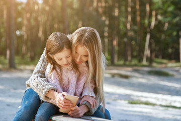 Mother holds laughing daughter and show her smart phone