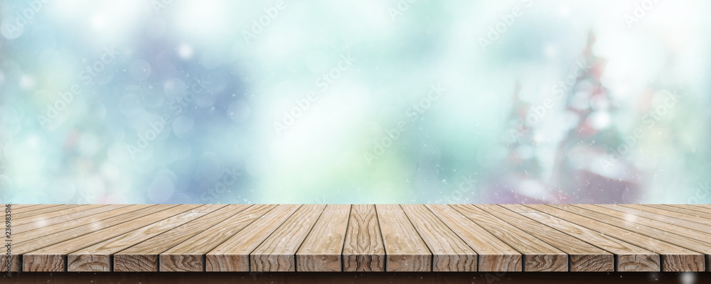 Aufkleber Wood table with abstract blur christmas tree and snow fall background with bokeh light.Mock up banner for display or montage of product.