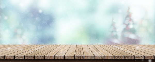 Wood table with abstract blur christmas tree and snow fall background with bokeh light.Mock up banner for display or montage of product.
