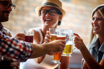 Young cheerful people in the beer pub drinking and having good time