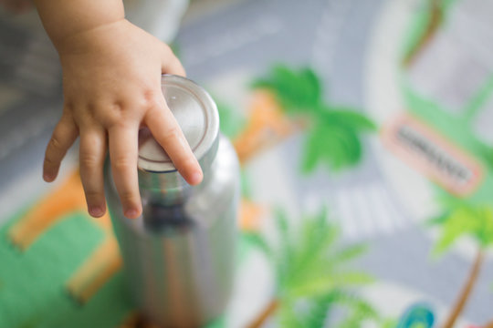 Baby Hand Grabbing Stainless Bottle In The Living Room