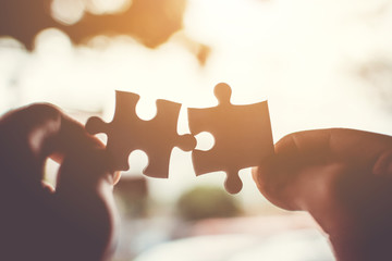 Two hand connecting jigsaw puzzle. Concept of partnership and teamwork in business strategy